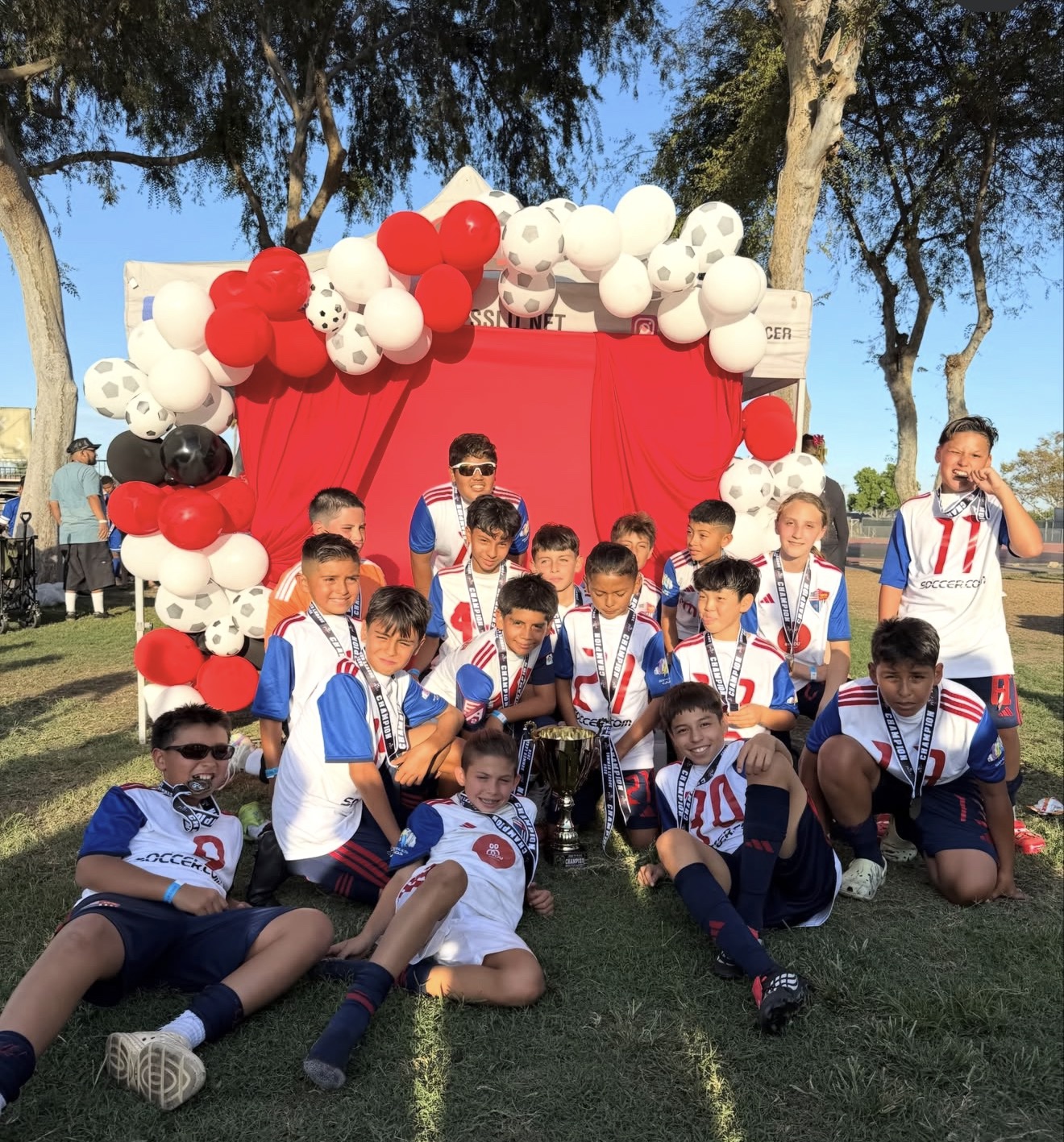 TFA-SELA BU13 White players gathered around a trophy